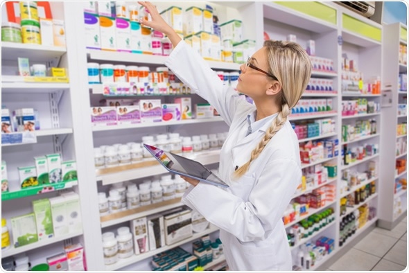 Pharmacist taking medicine from shelf in the pharmacy - Image Copyright: wavebreakmedia / Shutterstock