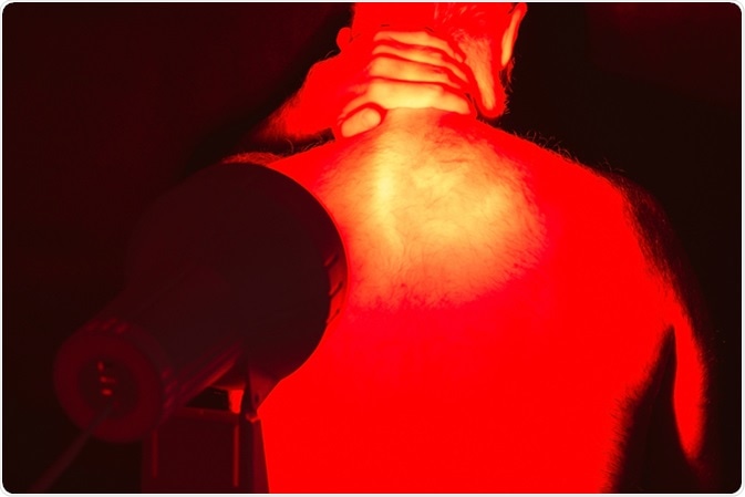 Back pain. Infrared heat light lamp therapy. Image Credit: Jaroslav Moravcik / Shutterstock