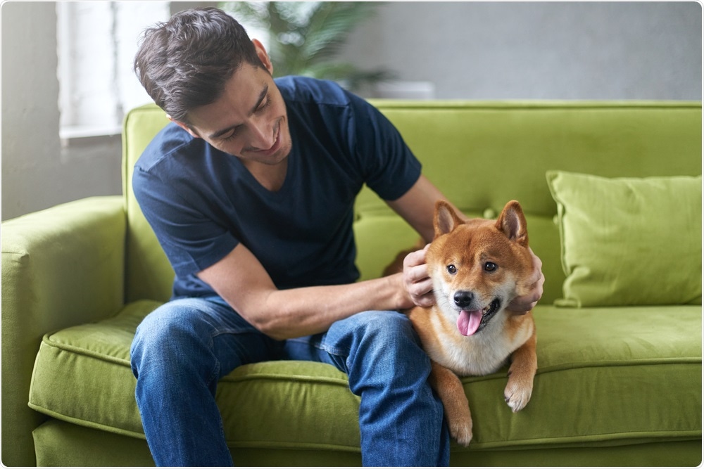 Student stroking dog on green sofa.