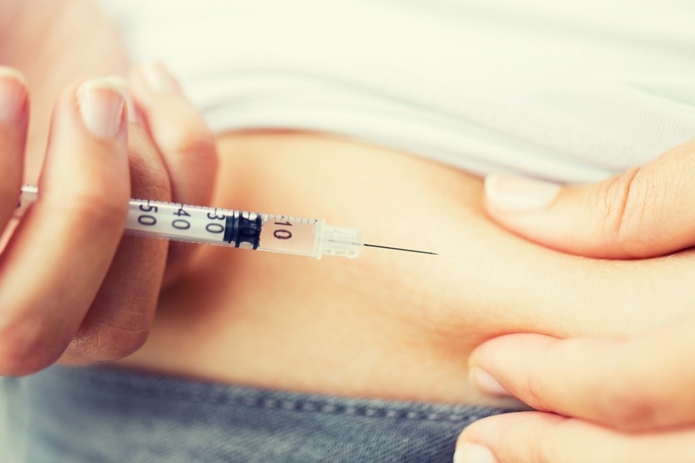 Close up of woman with syringe making insulin injection to himself at home. Image Credit: Ground Picture/Shutterstock.com