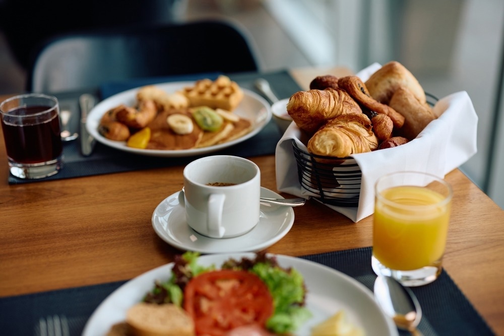 Close up of cup of coffee and buffet breakfast in hotel restaurant.