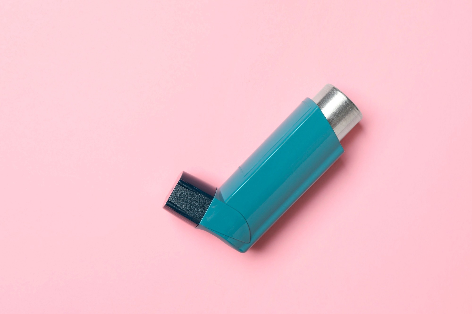 Asthma inhaler on pink background.
