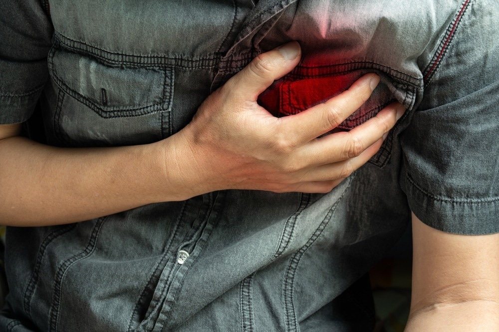 Man is sick and in pain and uses his hands to squeeze his chest