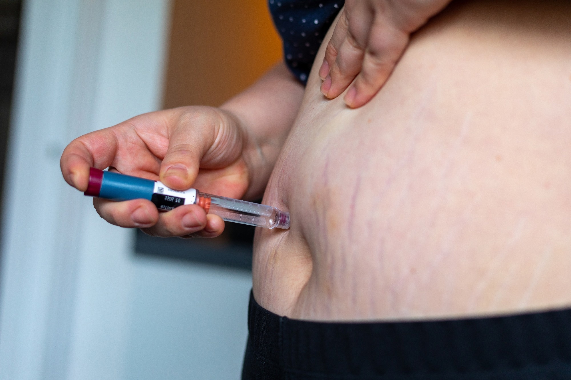 Overweight woman applying diabetes medicine injection into her belly