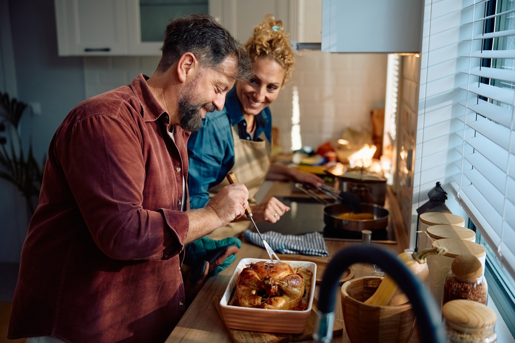 Happy man and his wife preparing roast turkey
