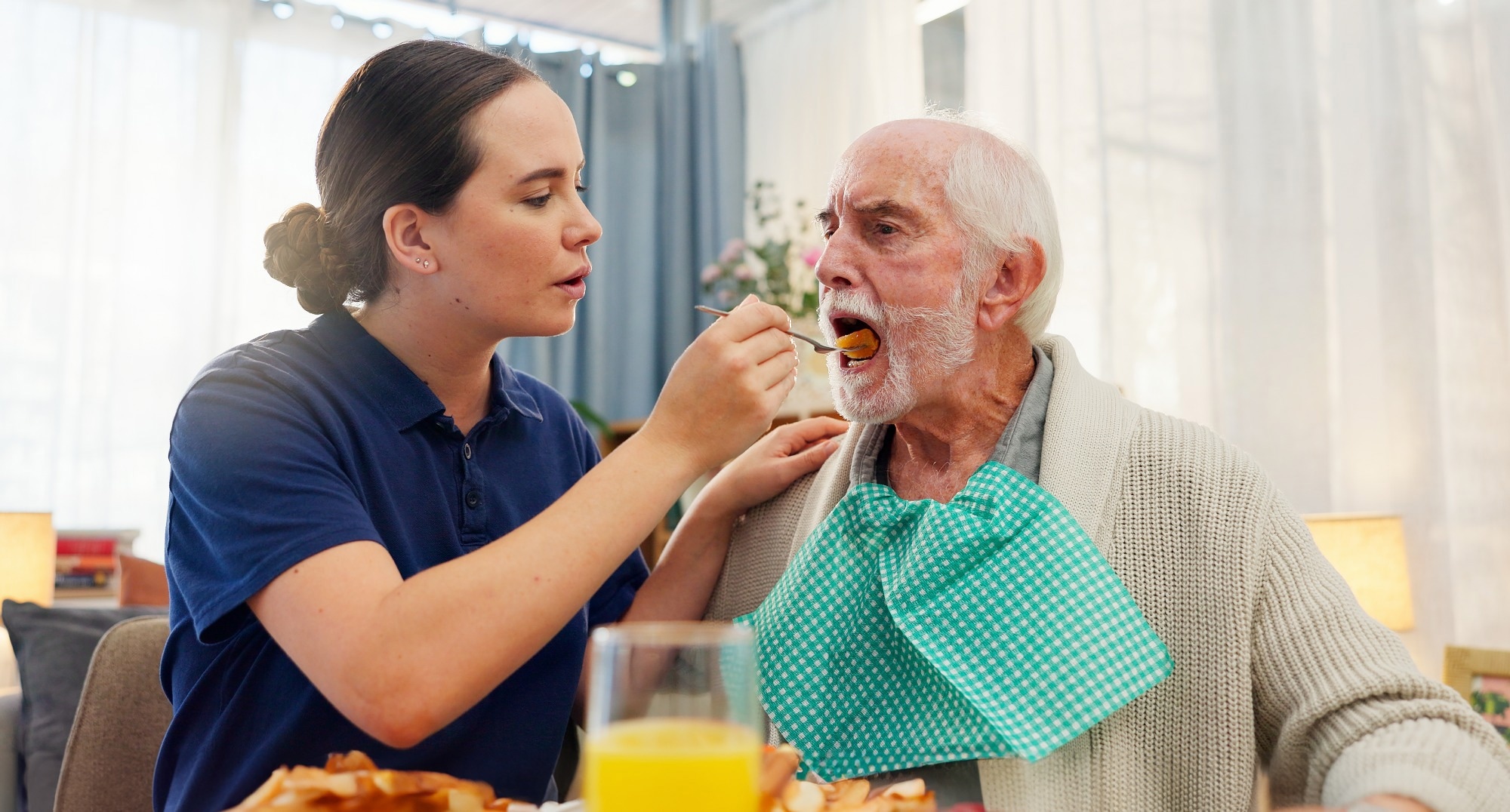 Female healthcare work feeding an elderly male patient with a spoon