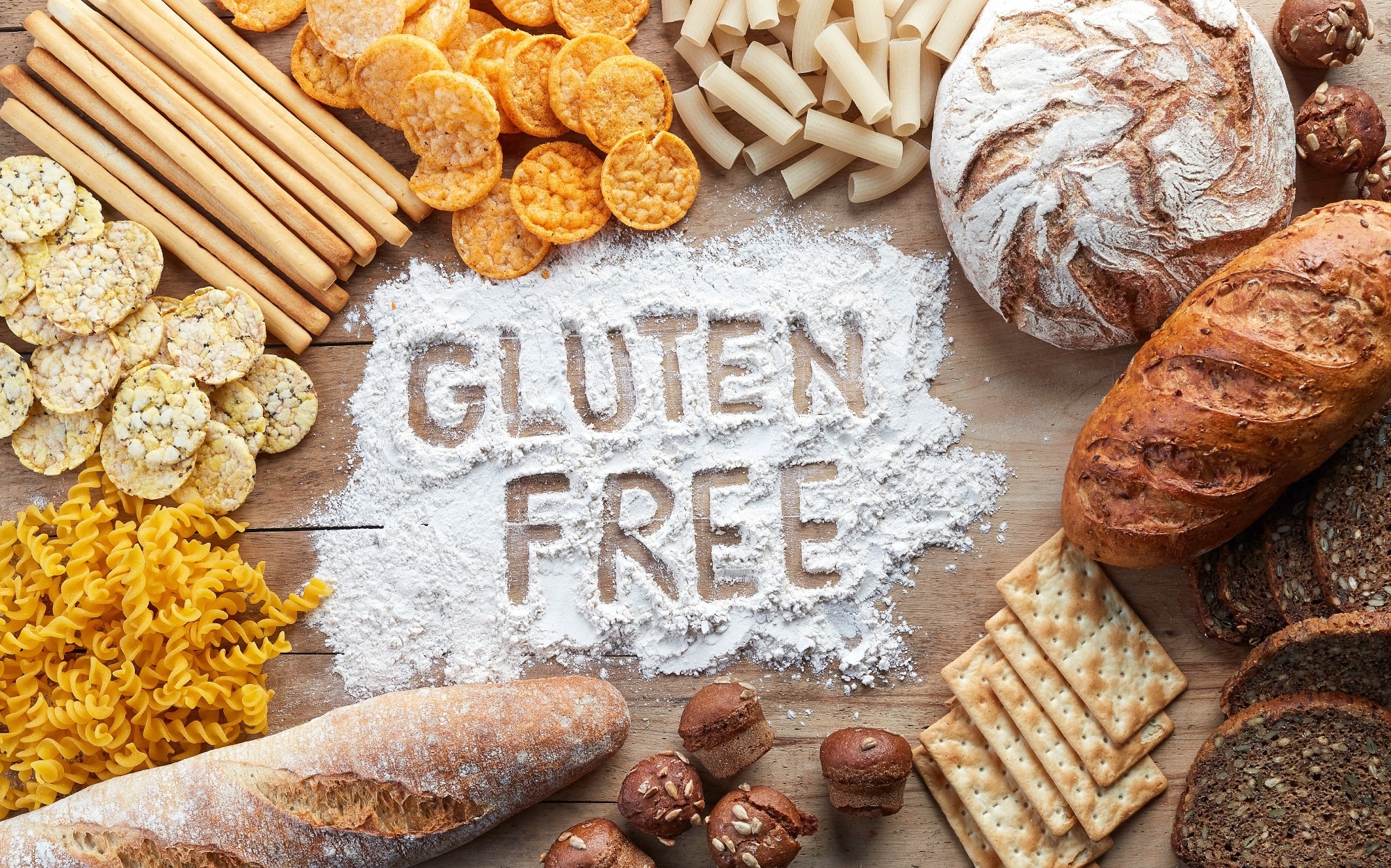 Gluten free food. Various pasta, bread and snacks on wooden background from top view