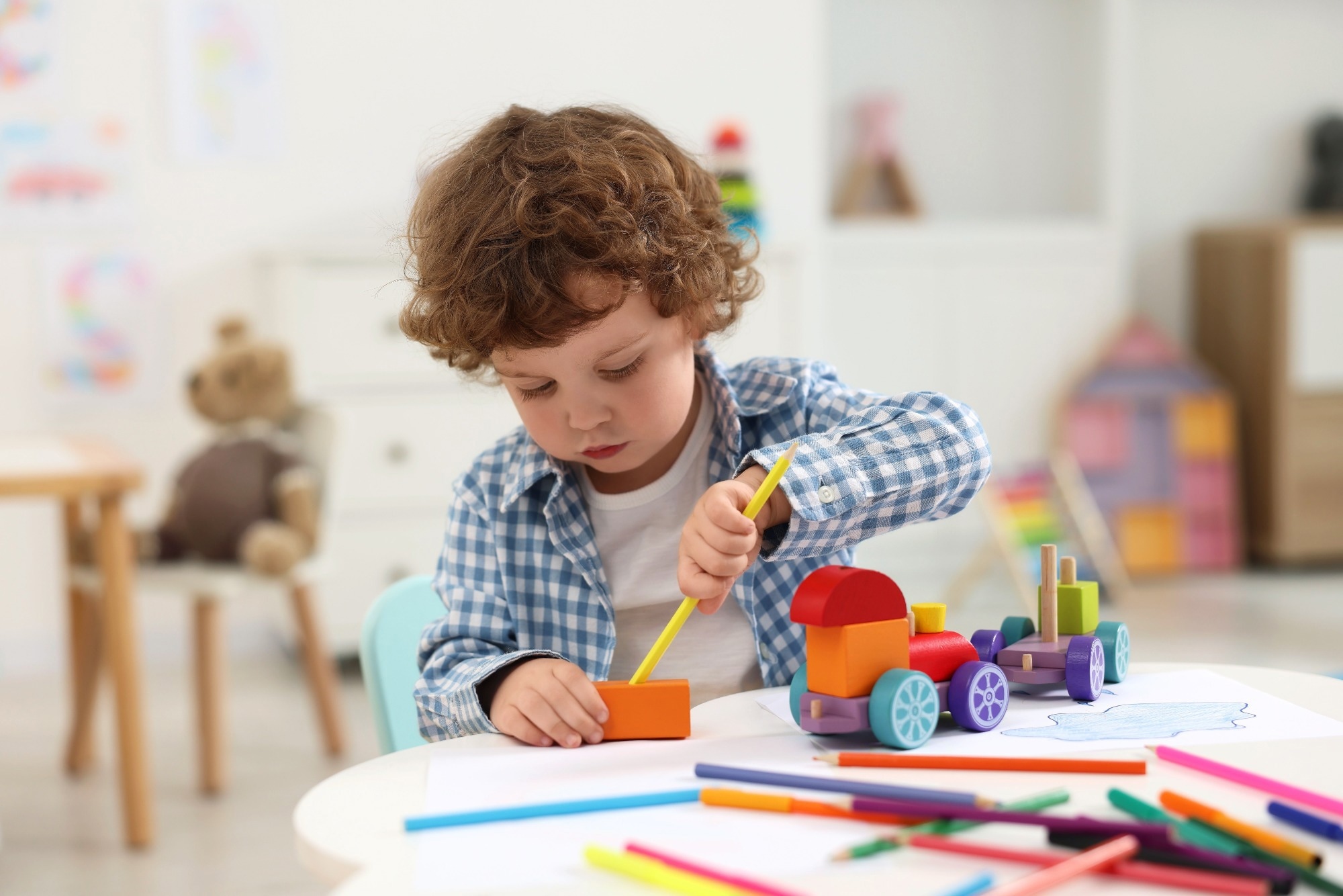 Young boy playing with wooden toys at white table in kindergarten